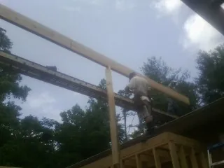 Carpenter setting a ridge beam over a new addition frame — Ice Dam Removal by Roofing Brothers in Basehor