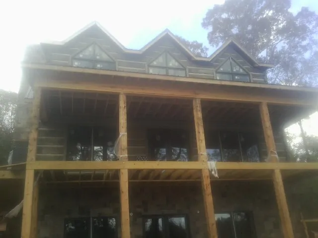 Dormers and porch framing on a large log home under construction — Roof Coating work by our crew in Basehor