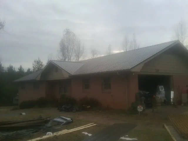 Gray metal roof on a stucco house with an attached garage in Basehor