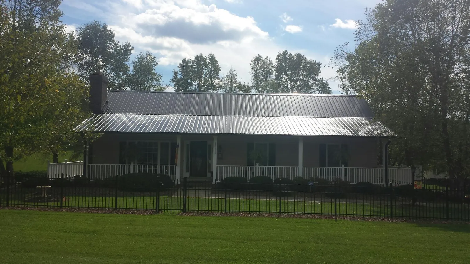 Gray metal roof on a brick ranch with a full width front porch — Gutter Guard Installation work by our crew in Basehor