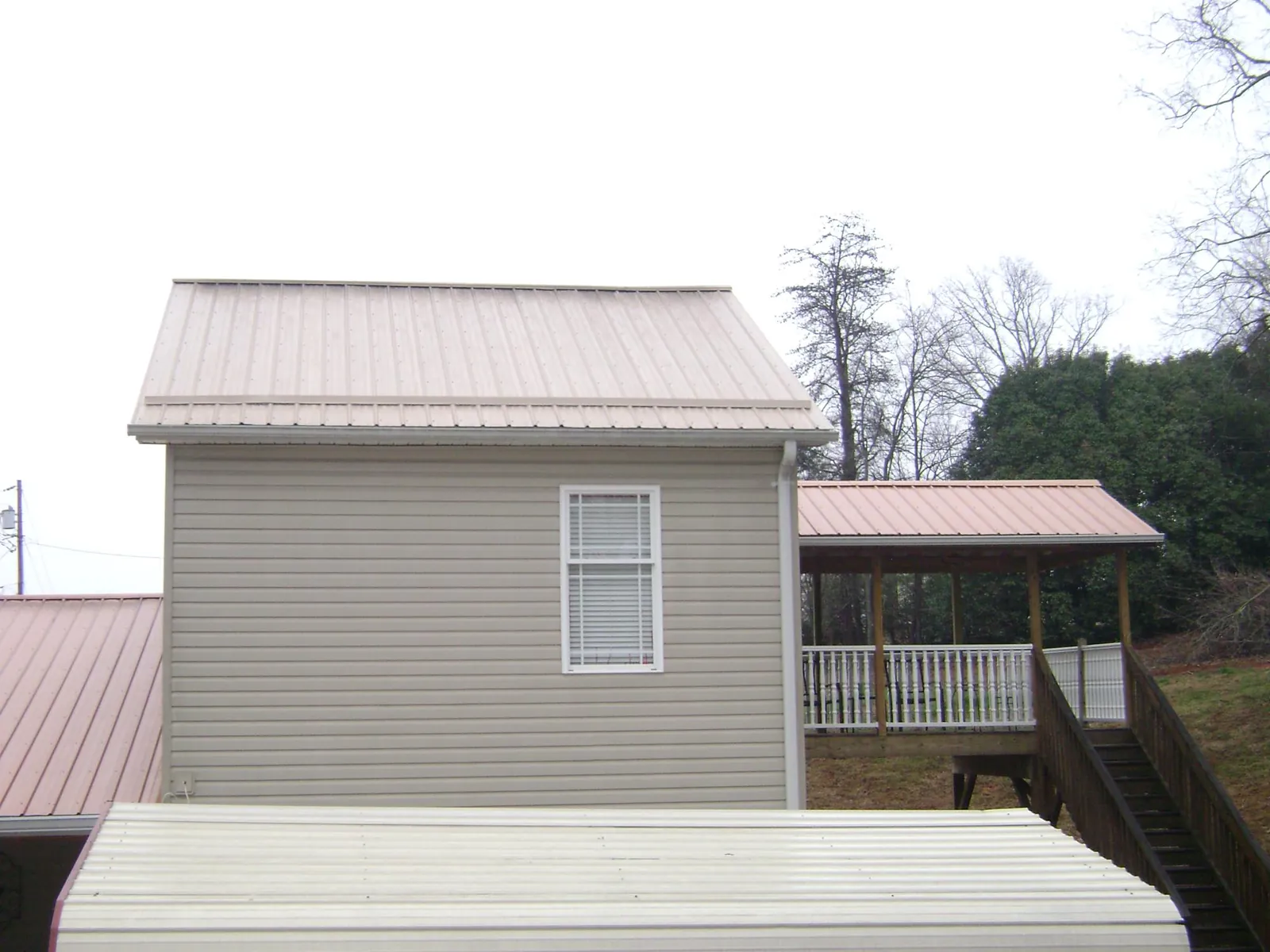 Tan metal roofs on a two story addition and attached porch, from a Roof Replacement job in Basehor