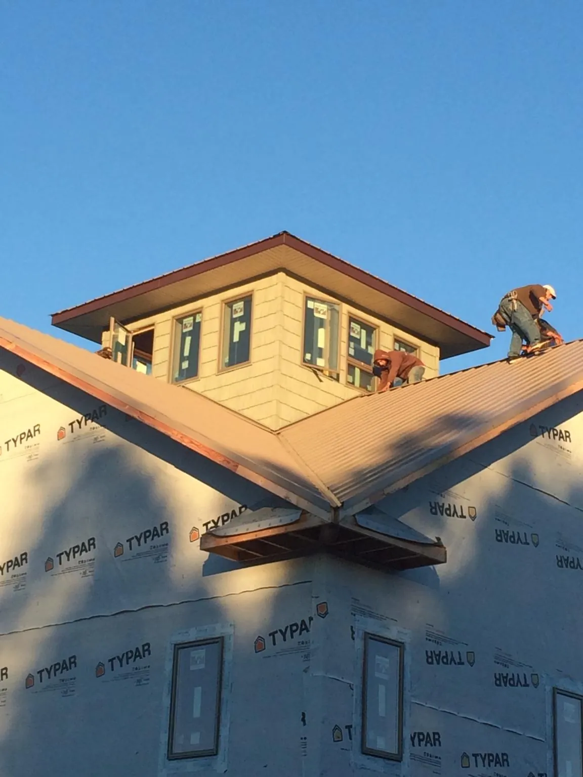 Roofers working around a rooftop cupola on a new metal roof at sunset — Roof Waterproofing in Basehor by Roofing Brothers